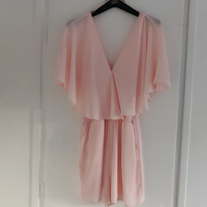 Playsuit - Sötaste byxdressen från Gina. Ljusrosa med volanger och knytning baktill (se bild). Dressen har fickor och resår i midjan som döljs av volangen när man har den på. Säljer pga för liten, endast använd fåtal gånger🌺 Kan mötas upp i Uppsala alt skicka mot att köparen står för frakt.