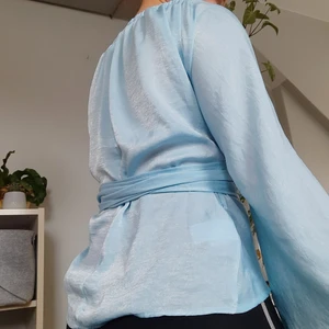 Wrap "Blus" - Ljusblå wrap-blus/topp, man kan välja lite själv hur man vill att den ska sitta. Ovan är bara ett exempel. Satin, tunnt tyg. Strlk s från bikbok