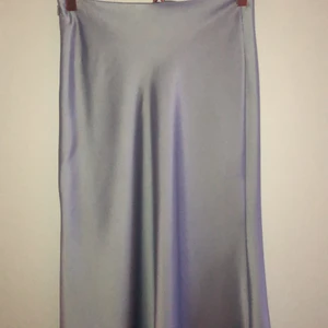 Kjol i silkes imitation från NA-KD - Kjol i Silkesimitation från NA-KD. Lavendelfärgad. Aldrig använd då det är fel storlek för mig, så det är i ny skick. Kjolen är lång och går nedanför knäna. Det är en dragkedja i sidan. Köpte den för 550kr säljer för 120 eller högsta bud. Köparen står för frakten 