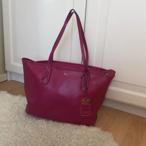 Lauren Ralph Lauren Totebag  - Supersnygg väska från Ralph Lauren i rosa, kommer med orginala dustbagen! Använd men väldigt varsamt, den är i superfint skick! Köptes för 1500 kr, budgivning från 550 kr äkta läder!!