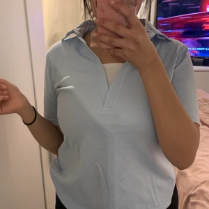 Blå skjorta, med vit strand över brösten - En super fin blå ”skjorta”. Färgen är babyblue och har ett skönt material. Knappt använd och skulle passa nästan alla klädstilar. Rekommenderar att använda denna under sommaren!