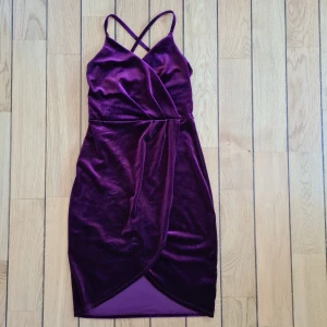 Vinröd festklänning i sammetsliknande material  - Vinröd klänning i sammetsliknande material med slits fram och kryss i ryggen av axelbanden. Aldrig använd då den är för liten för mig som normalt är en 38. Går till knäna bak och lite kortare fram på mig som är 164 cm. 