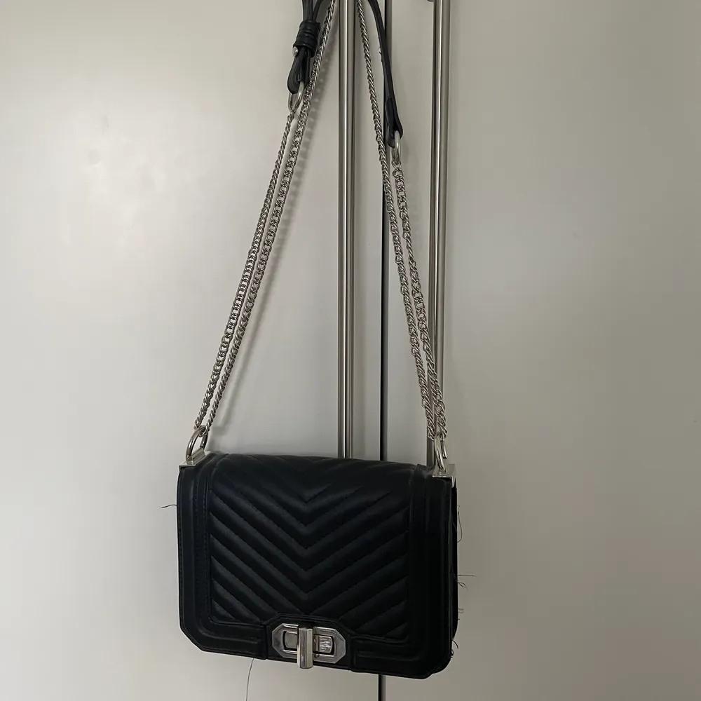 En svart handväska med silver kedja . Väskor.