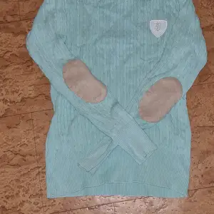 En blå långärmad tröja  från jacson den har armbågs förstärkning på båda armbågarna och inga skador 
