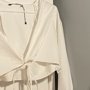 Kort vit skjorta  - Säljer en vit kortare skjorta från zara. Jätte fin på sommaren när man är brun eller nu till våren. Man knyter själv och den går lite under brösten på mig.🥰