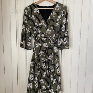 Klänning - Jättefin olivgrön klänning från MQ! Använd en gång och säljs endast för att den inte kommer till användning :( dragkedja i ryggen och knyt i midjan. Strl 36, något smal i midjan.