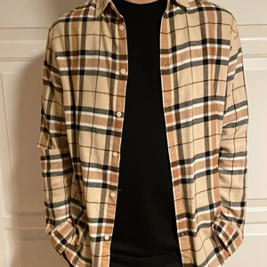 Rutig skjorta från H&M - Beige/svart rutig skjorta från H&M i strl.L, säljes pågrund av att den inte längre kommer till användning. Nypris 199kr säljes för 100kr+frakt, köparen står för frakten.