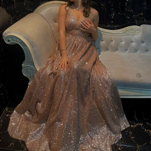 Mr & Mrs collection i storlek 40/38 - Lång klänning i färgen roseguld, glittrig och stängd vid rygg och lite öppen vid brösten, den är använd endast 1 gång och den är ny!