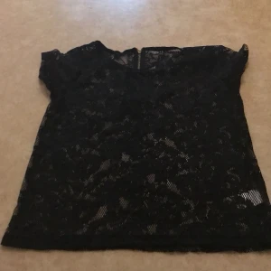 Svart tshirt - En svart hålig tshirt med blommönster! Har använts en gång för länge sen! På baksidan är det en dragkedja!