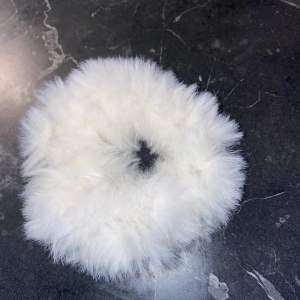 En vit handgjord scrunchie. Tillverkad av Fur Lux garn. 