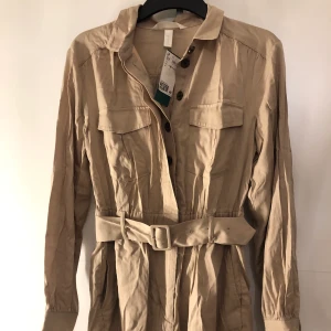 Beige byxdress  - En beige långärmad byxdress, köpt från h&m. Storlek 36. Aldrig använd, (den är skrynklig för att den varit i min byrå) jätte snygg på sommaren