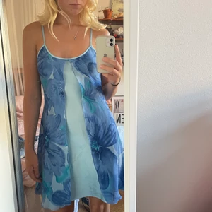 Ljusblå klänning/nattlinne - Så söt ljusblå klänning som tyvärr ej kommer till användning. Den har ett undre lager i siden och ett övre lager i ett lite genomskinligt tyg med blommigt mönster. Står ej storlek men passar mig med s. Den har justerbara axelband men ena är trasigt och lagat med en säkerhetsnål, går säkert att fixa på ett bättre sätt också. Möts i Stockholm annars betalar köpare frakt!