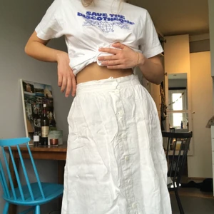 Vit midikjol med knappar - Vit midikjol (längd syns i bild 2) i linne med knappar hela vägen fram. Insydd underkjol som gör att den inte är genomskinlig. Vanligtvis inte lika skrynklig hehe...