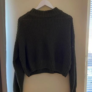 Stickad tröja - En mörkgrön stickad tröja från H&M. Längden på tröjan går lite längre än en magtröja, navelhöjd ungefär.