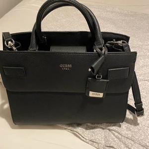 Guess väska  - Guess väska med axelremm. Väskan har tyvärr aldrig kommit till användning och är i nyskick.