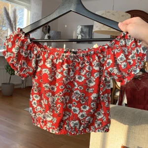 Gullig blommig offshoulder  - Röd offshoulder magtröja(?) med blommor 🌺 Använd men fortfarande mjuk och i bra skick, från Gina Tricot i storlek S! 💕