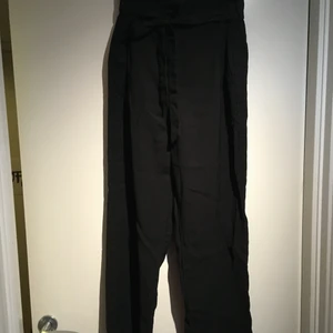 Svarta lösa byxor med rosett - Svarta, vida byxor med snörning i midjan. Köpta på H&M för några år sedan, men inte använt så mycket. De är i storlek 38 men passar som S. Bra skick. 