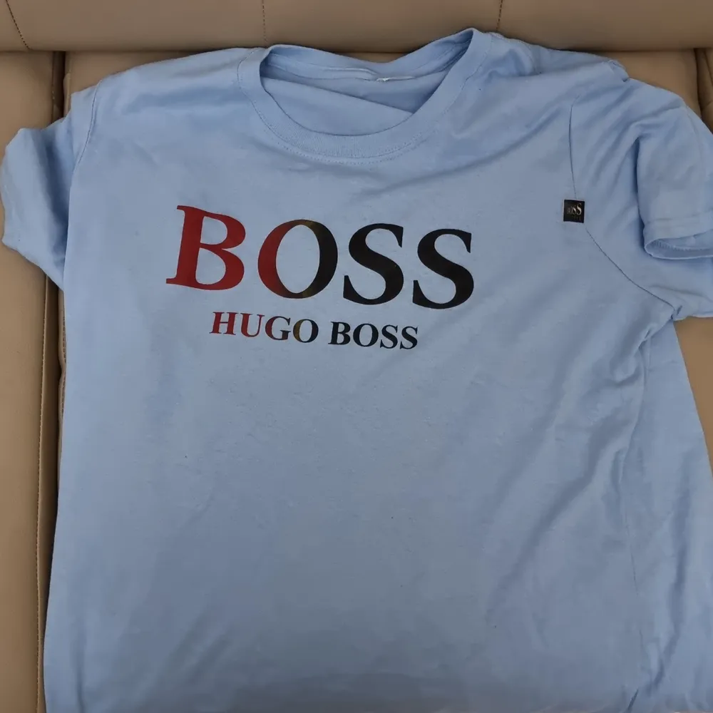 Oanvänd Hugo Boss t-shirt med centrerad text och ljusblå bakgrund. Simpel design funkar med det mästa. Framhäver dina armar och är väldigt behaglig att ha på sig.       (!Tar häldst swish!). T-shirts.