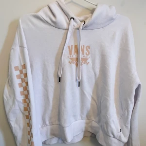Vans hoodie  - Hoodie av lite kortare modell, använd ett fåtal gånger men trots det en aning noppig. Vit med ljusrosa text, galet mjuk på insidan.