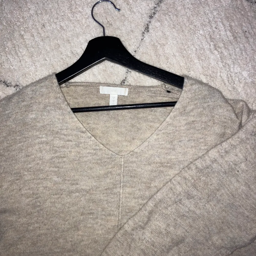 V-ringad stickad tröja i beige/grå färg. Bjuder på frakt vid snabb affär. Stickat.