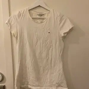 En vit t-shirt från Tommy Hilfiger i storlek S. Lite längre men tajtare passform. Har nästan aldrig använts och är i nyskick. 