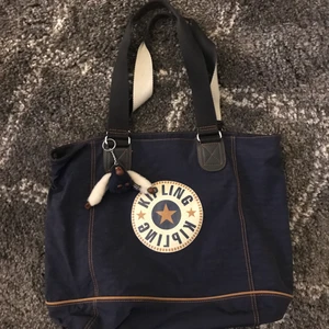 Kipling purple waterproof tote - Kipling purple/blue tote with red interior. In excellent condition. Comes with crossbody strap and classic Kipling monkey keychain. 