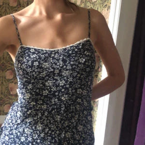 Blommig sommarklänning - Klänning med ursött blommönster som jag säljer då den inte sitter så bra på mig. Är i bra skick men ett av banden är trasigt så går inte att justera. Har en innerkjol så den är inte genomskinlig alls. Står tyvärr varken storlek eller märke. Den tas på utan dragkedja men är stretchig i ryggen så det borde inte vara något problem. 