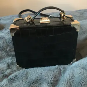 Like new! Aspinal of London classic trunk in black croc leather with red interior. Comes with dustbag and crossbody strap. Perfect condition, only worn a couple of times. Original price over 5000 SEK. Purchased from Vestiaire Collective.