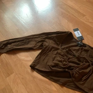 topp - En festligare brun topp med en söt knytning vid byst! Helt oanvänd och prislapp kvar. 