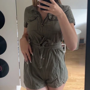Militär grön playsuit - Playsuit ifrån H&M! Militär grön med militär knappar. Short plus skjorta/topp! Super fin😍 💚Strl S💚 Oanvänd! 