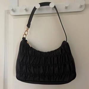 Väska från shein - Liten svart väska med gulddetaljer från shein. Sparsamt använd och hel och ren. Bra kvalitet och en ordentlig dragkedja. Köparen står för frakt. 