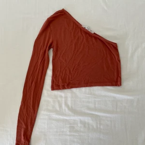 One shoulder topp från NA-KD - En one shoulder i kopparnyans från NA-KD. Storlek S men passar även en som bär storlek M och den sitter oerhört fint. Pris: 80kr. Finns i Halmstad eller Kalmar annars står köparen för frakt. 
