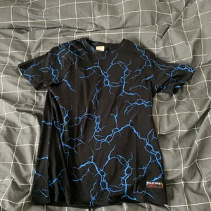T-shirt - Säljer en t-shirt med fint blått blixt tema. Är osäker på vart den kommer ifrån dock. 