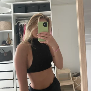 Svart linne med hög krage - Svart linne med hög krage samt cool detalj i ryggen, storlek M men passar även S. (köpt från Junkyard)