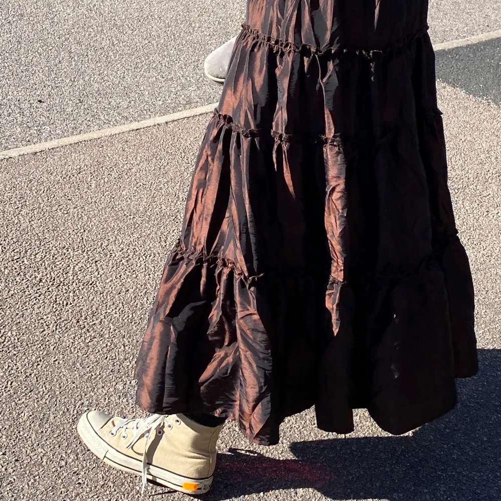 En fin brunglänsande volangliknande kjol. Fint material som lyser i solen. Köpt secondhand men i väldigt bra skick💕 står ingen storlek men är en tjock resor i midjan så passar typ xxs - M/L tror jag.                                                       . Kjolar.