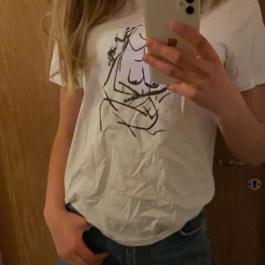 vit tröja med tryck på - (förlåt för dåligt ljus) säljer denna t-shirt från NA-KD var av att jag tycker den sitter tajt. Köpare står för frakten