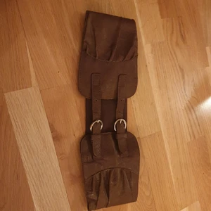 Brunt bälte - Brunt brett midje bälte med guldfärgade metallspännen. Elastisk baktill. Ca 80cm innermått ned yttersta spännet knäppt. Obs!! Finns även i svart. Båda från H&M. Kan skickas på valfritt sätt, köparen betalar frakten.