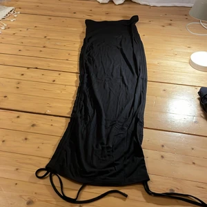 Lång svart kjol - Detta är en lång svart kjol från Shein. Oanvänd endast provad. Säljes för att den inte passade. Väldigt stor i storleken. Satt bra i midjan men väldigt lång. Knyten där nere.