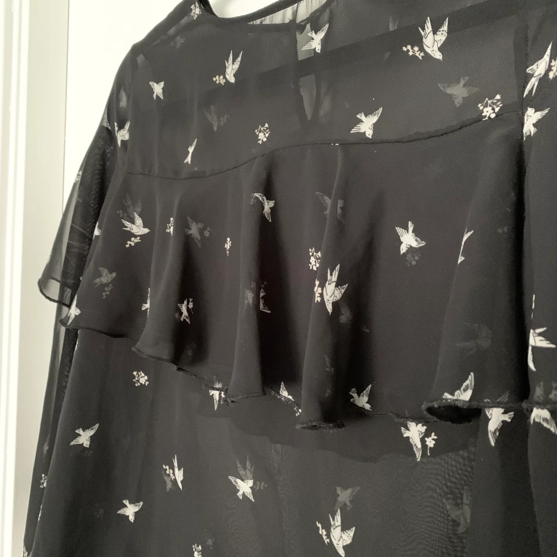 Svart blus med fågel motiv och volanger  - 90