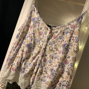 Blommig topp - Så söt blommig topp med spets längst ner och tygprydda knappar 🥰 Köpt på BikBok. Snygg både med och utan BH under!