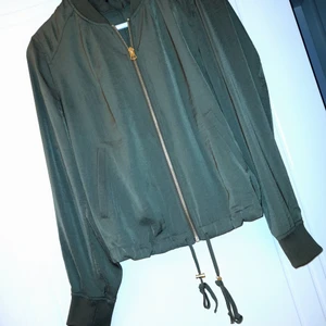 Militärgrön bomberjacka (tunn) - Bomberjacka i tunt material och i kortare modell. Färgen är dock finare i verkligheten. Den har aldrig använts förutom testats så den som gott som ny. Köpare står för frakt.