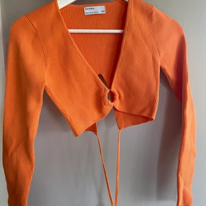 Orange topp från Bershka, storlek M - Orange långärmad topp från Bershka, ring i fram och knytning bak i ryggen. Storlek M, aldrig använd.