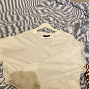 Vit tröja  - Vit tröja från Nelly med en fin skurning fram. Bra skick endast använd 4-5 gånger. 