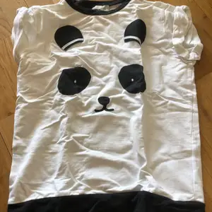 Vit t-shirt tröja liknande en björn svarta motiv.