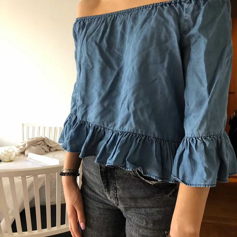 Denim färgad offshoulder blus med volang detaljer. Original pris 400kr. Blusar.