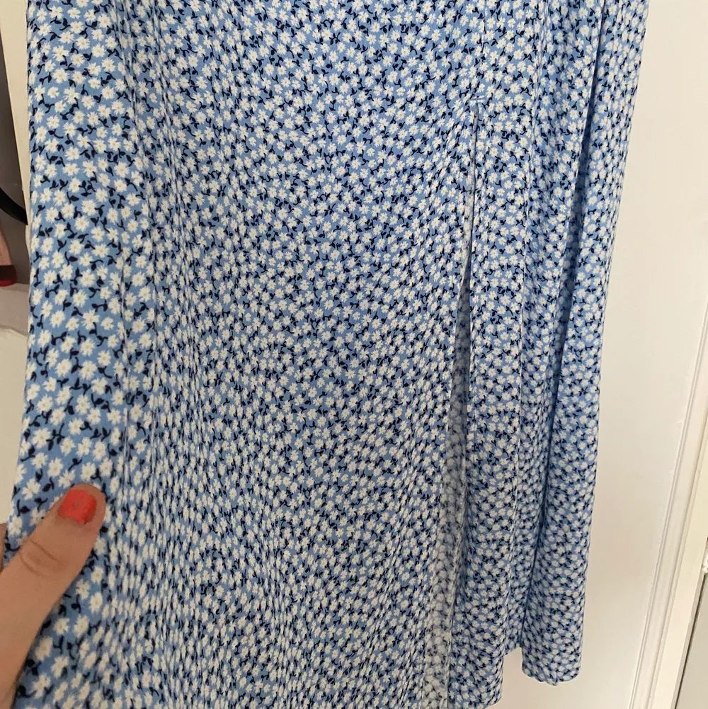 En lång blå kjol med blommigt mönster. Kjolen är aldrig använd och är i storlek 40. På ena sidan finns det en slit.. Kjolar.