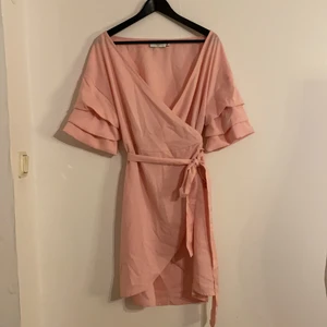 Rosa sommarklänning str 38 - Säljer denna fina sommarklänning från NAKD. Klänningen slutar ungefär mitt på låret. Knytning i midjan som man själv kan bestämma hur hårt man vill ha🌸 Aldrig använd. Pris 100kr + frakt 