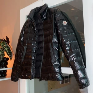 Monclerjacka strl S  - Glansig Monclerjacka dammodell. Storlek S/M. Den har några år på nacken och skulle behöva lämnas in till en skräddare för nya dragskor till dragkedjorna både framtill och till fickorna. Annars i fint skick. Inga hål eller liknande. 