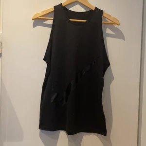 Nike träningslinne  - Svart träningslinne från Nike med hög framsida och bred brottarrygg. Stor svart, glansig Nike-logga på framsidan. Mycket bra skick. 