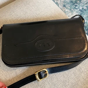 Handväska - Liten söt svart handväska med guldiga detaljer och många fack. Köpt secondhand, använd fåtal gånger. Anpassningsbart band, går att göra fler hål för att anpassa efter rätt längd